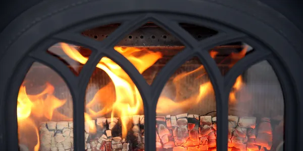 A roaring fire inside a clean, arched fireplace insert
